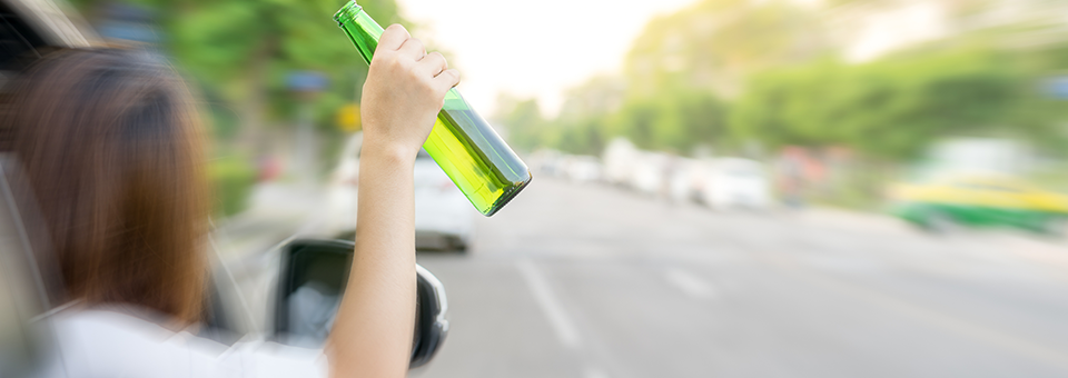 photo of drunk girl hanging out of car window on road with beer in hand